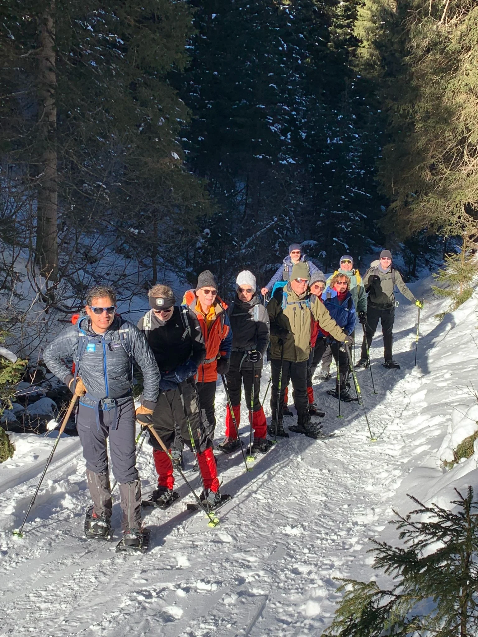 Eine Gruppe Schneeschuwanderer steht vor dem Wald und lässt sich von der Sonne bescheinen | © DAV Flensburg