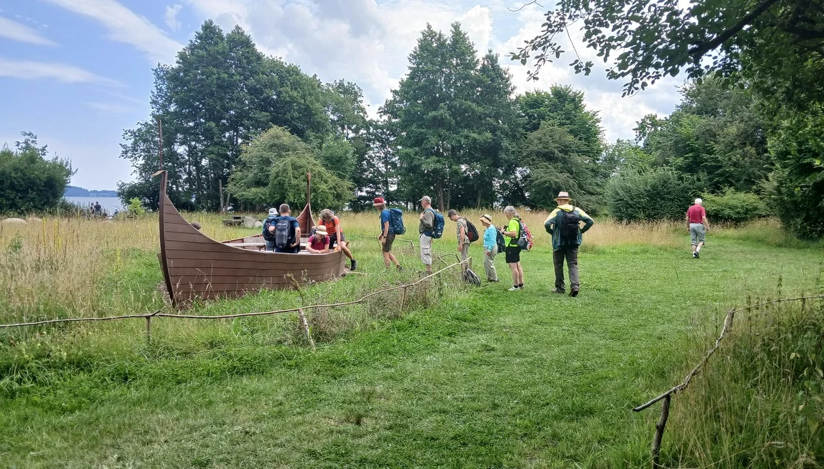 Eine Gruppe Wanderer beim Besteigen eines Wikingerbootes | © Kai Vermehren
