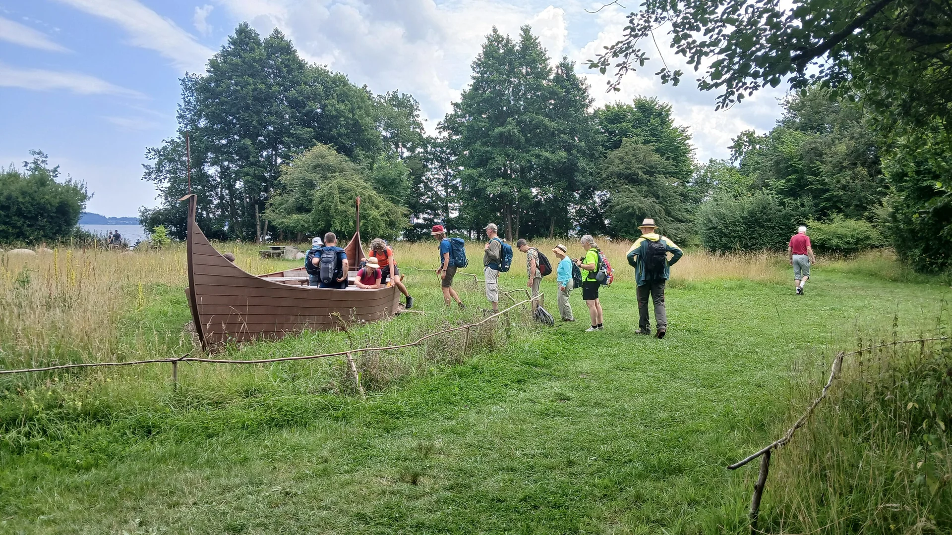 Eine Gruppe Wanderer beim Besteigen eines Wikingerbootes | © Kai Vermehren