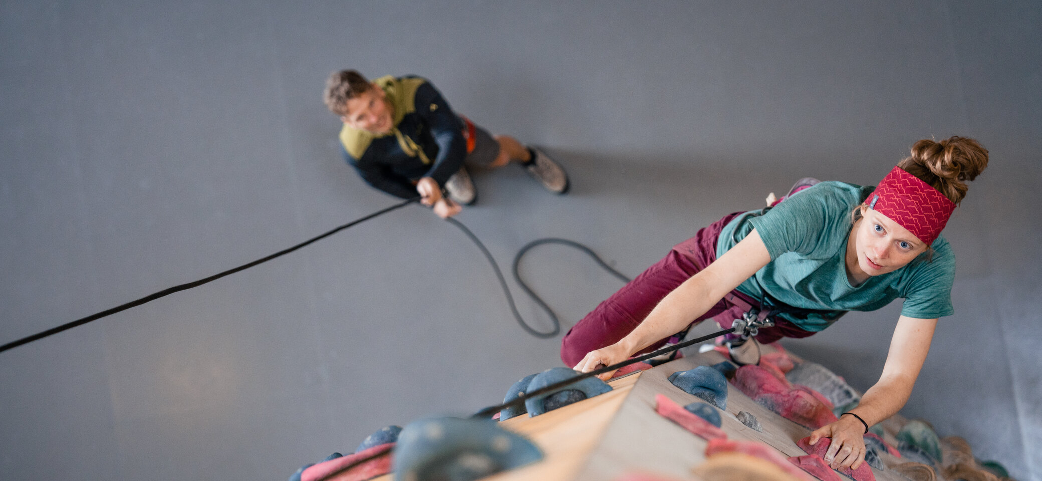Eine Frau klettert in einer Kletterhalle, ihr Partner sichert sie. | © DAV/Marisa Koch